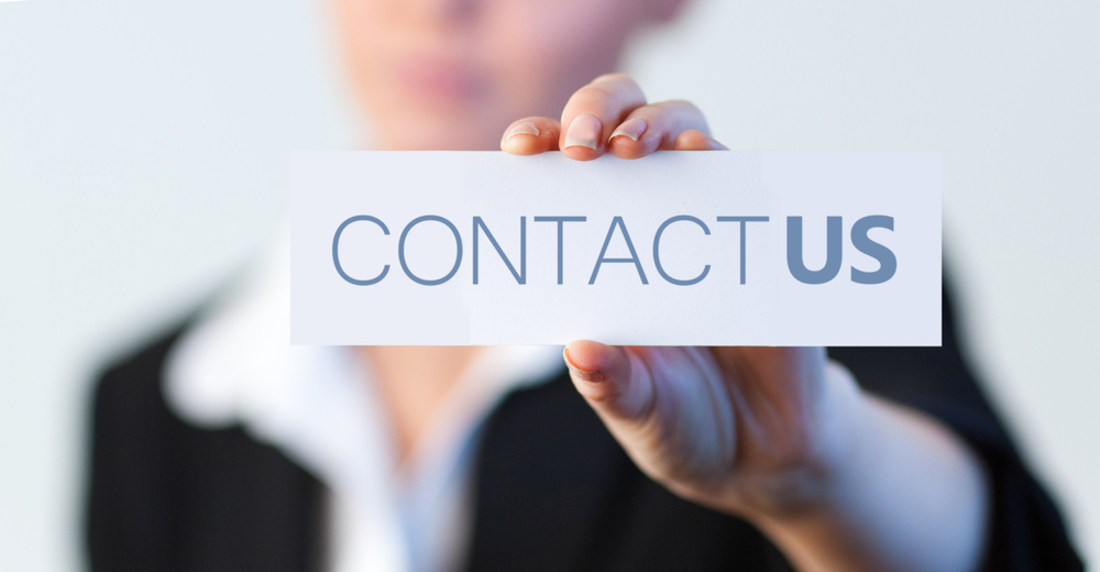 Businesswoman holding a label with contact us written on it with focus on her hand